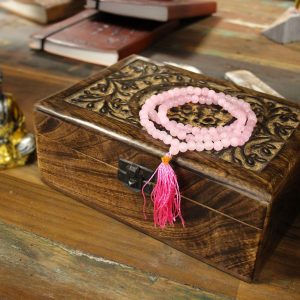 Mala 108 perles en quartz rose naturel avec pompon rose posé sur coffret en bois