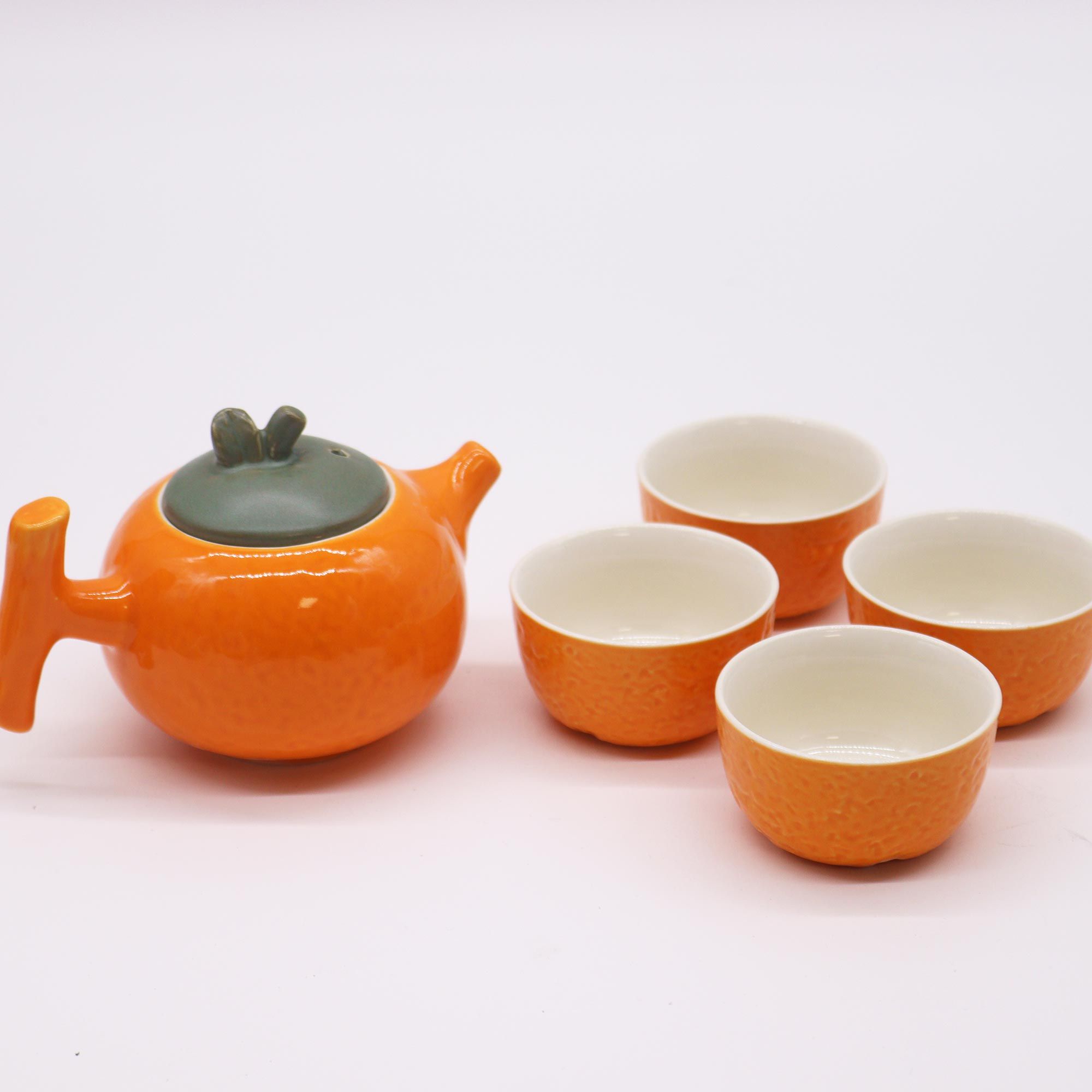 Théière en céramique en forme d'orange versant du thé dans des tasses assorties - Lumen Arca