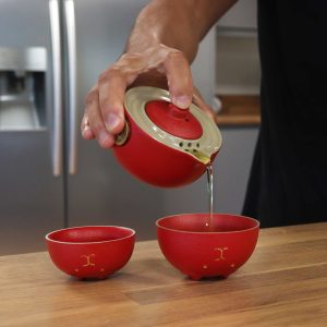Versement du thé depuis la théière chat porte-bonheur rouge